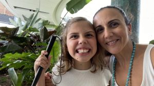 Girl with a white cane smiling and her mum giving her a cuddle