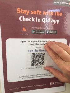 a finger finding the qr code on a covid 19 check in poster