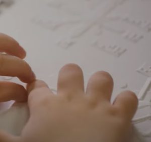 Close up of a child's hands reading a tactile map.
