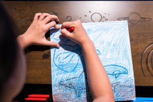 a child making a picture of sea creatures using crayons